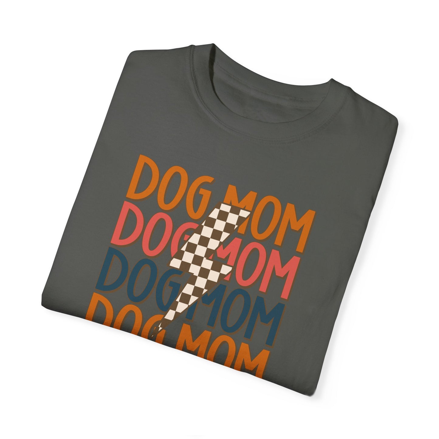 The Checkered Vibes Dog Mom Tee by Banks + Cove is a folded gray T-shirt featuring DOG MOM repeatedly in vibrant orange, blue, and red, with a beige checkered lightning bolt overlay for a retro look perfect for trendy dog moms.