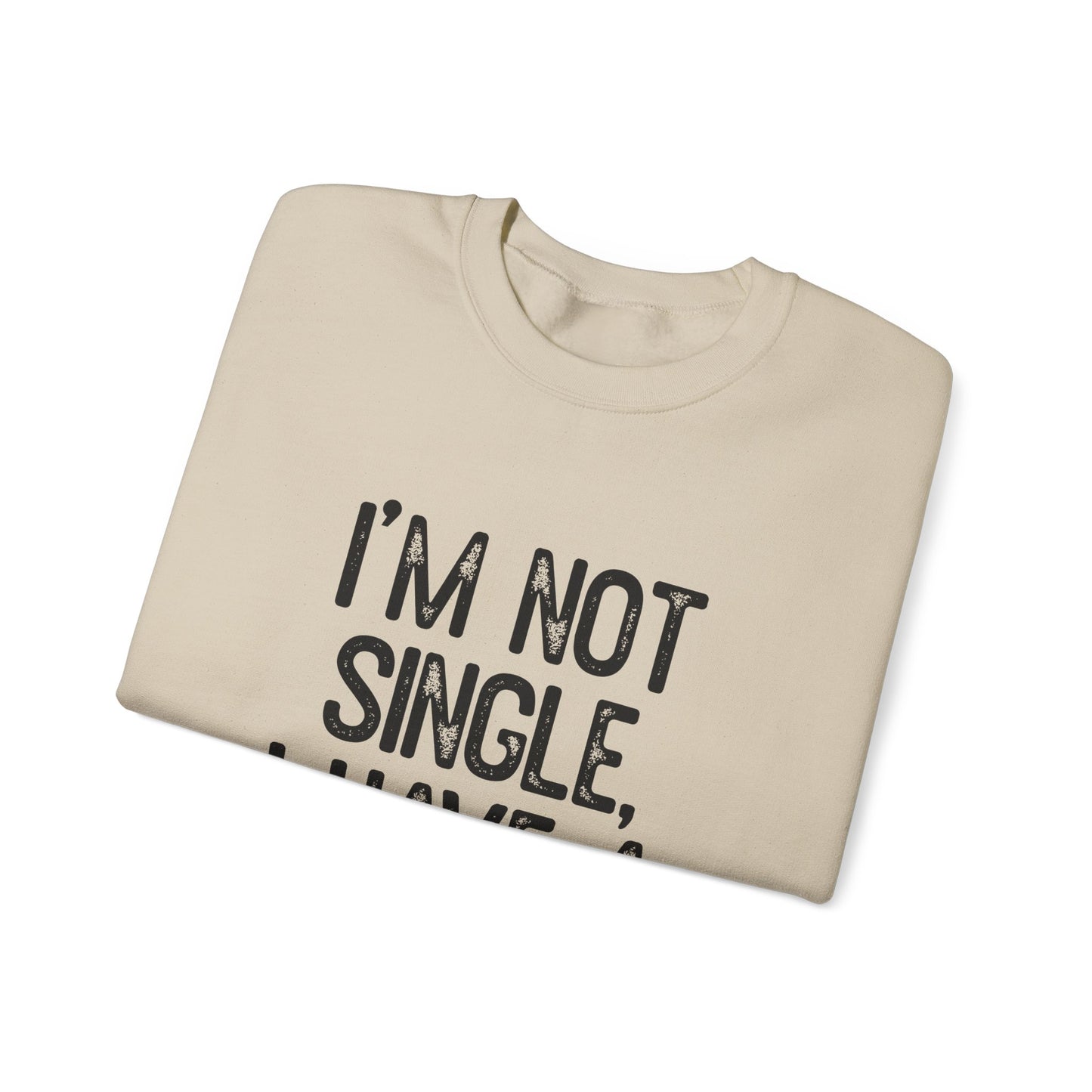 A folded beige sweatshirt features the bold black text Im Not Single, I Have A Dog. This cozy crewneck by Printify is perfect for dog lovers, adding a neutral touch against a plain white background.