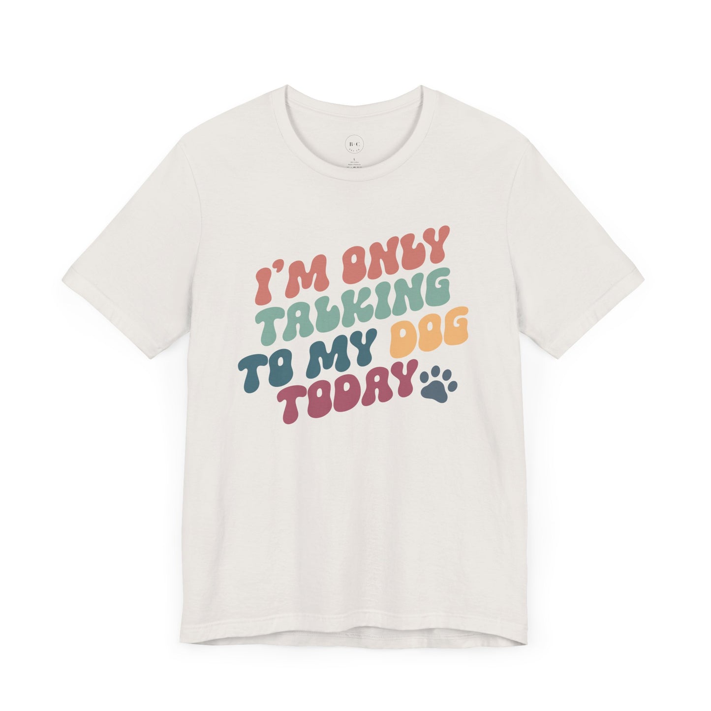 The Banks + Cove Funny Dog Lover Tee is a white unisex short sleeve shirt featuring vibrant red, orange, green, and blue text that reads IM ONLY TALKING TO MY DOG TODAY with a paw print. Perfect for any occasion.