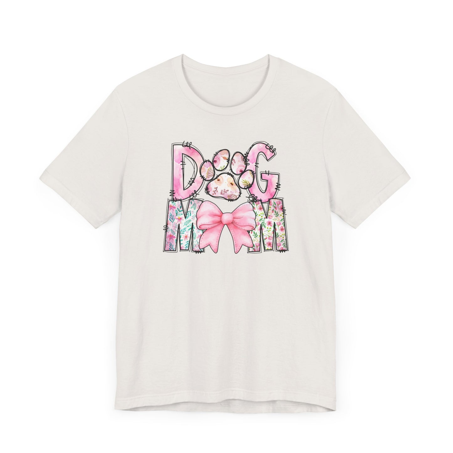 Introducing the Paws & Petals Dog Mom T-Shirt by Banks + Cove, featuring DOG MOM in watercolor floral letters, a pink paw print, and a large pink bow. Perfect for any proud pet parent!.