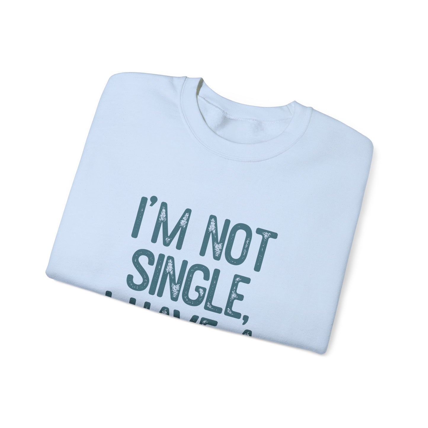 A folded Dog Lover Crewneck Sweatshirt by Printify features text IM NOT SINGLE, I HAVE A... in distressed dark teal font, with the rest hidden. Ideal for pet owners and dog enthusiasts, it sits against a pristine white backdrop to captivate and enchant.