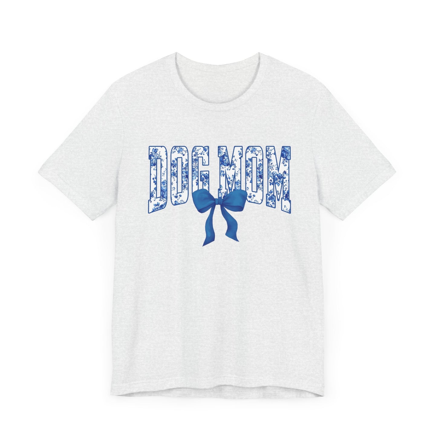 The Banks + Cove Dog Mom Blue T-Shirt is a white varsity-style tee with capital DOG MOM in a floral print and a charming blue bow beneath the text.