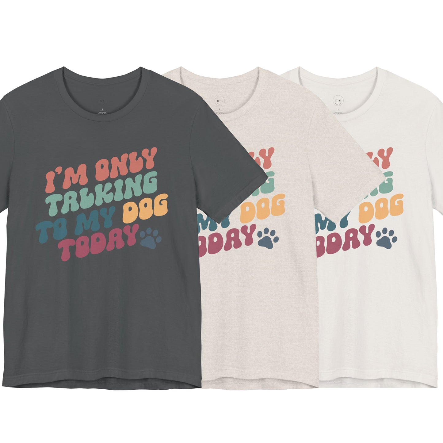 Banks + Coves Unisex Short Sleeve Funny Dog Lover Tee states Im Only Talking to My Dog Today and comes in dark gray, light beige, and white. Its playful design includes a colorful paw print, making it perfect for dog walks or relaxing with your furry friend.
