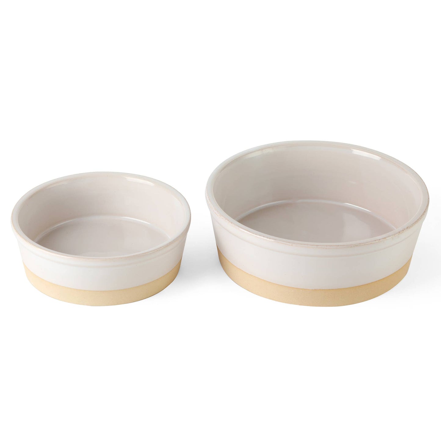 The Nordic Cream Pet Bowl set by Park Life Designs features two stylish bowls, one larger and one smaller, with beige exteriors and cream interiors. Crafted from potters clay base, they add an elegant touch to any setting against a white background.