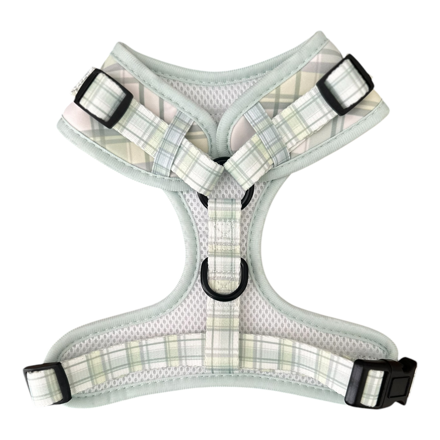 The Plaid About You Dog Harness by Banks + Cove features a light green plaid pattern, adjustable black buckles, a comfy mesh interior, and metal loops for easy leash attachment, ensuring functionality and an adjustable fit for your pet.