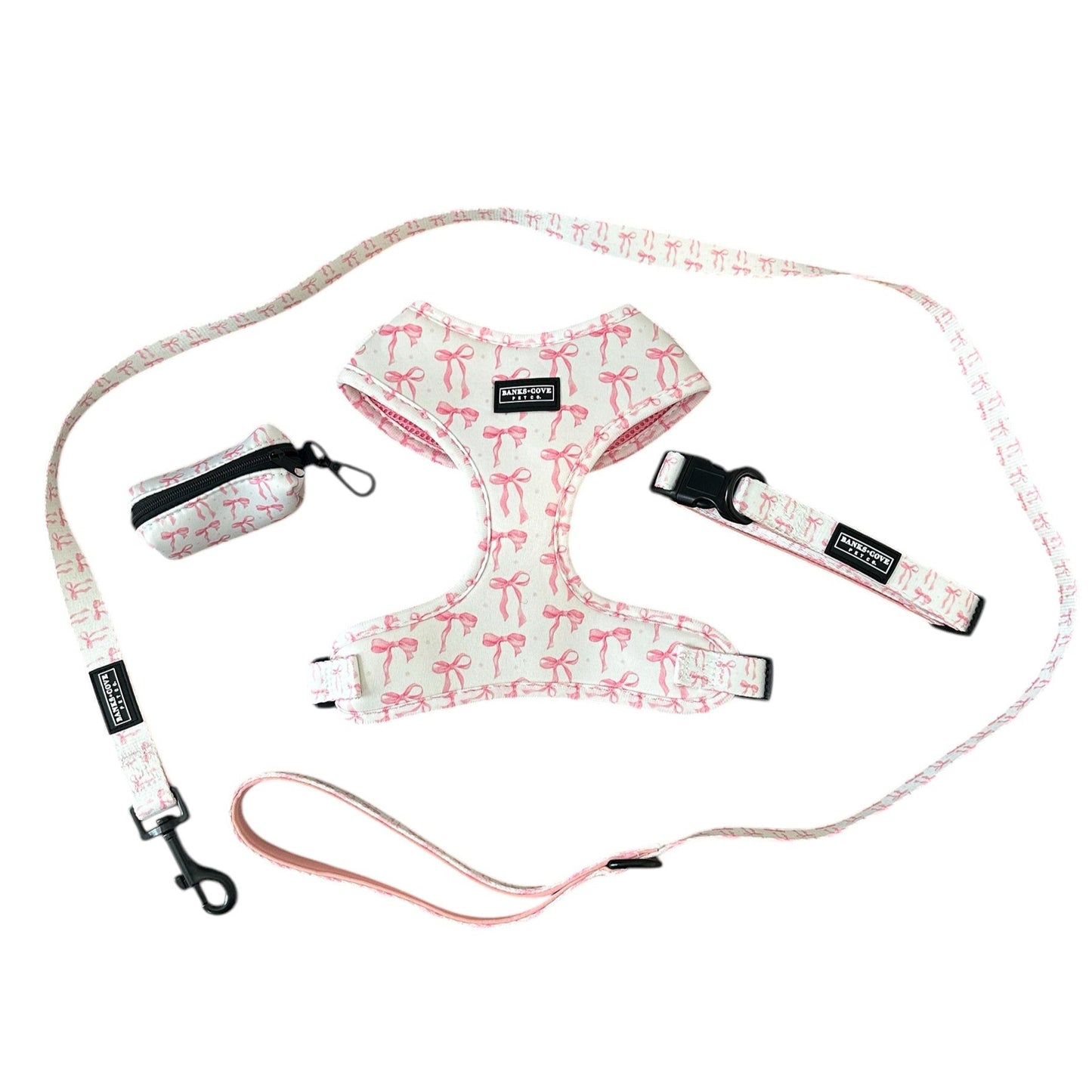 The Coquette Pooch 4 Piece Bundle Set by Banks + Cove offers chic dog accessories with a pink flamingo print, including a harness, leash, collar, and pouch crafted from high-quality materials.