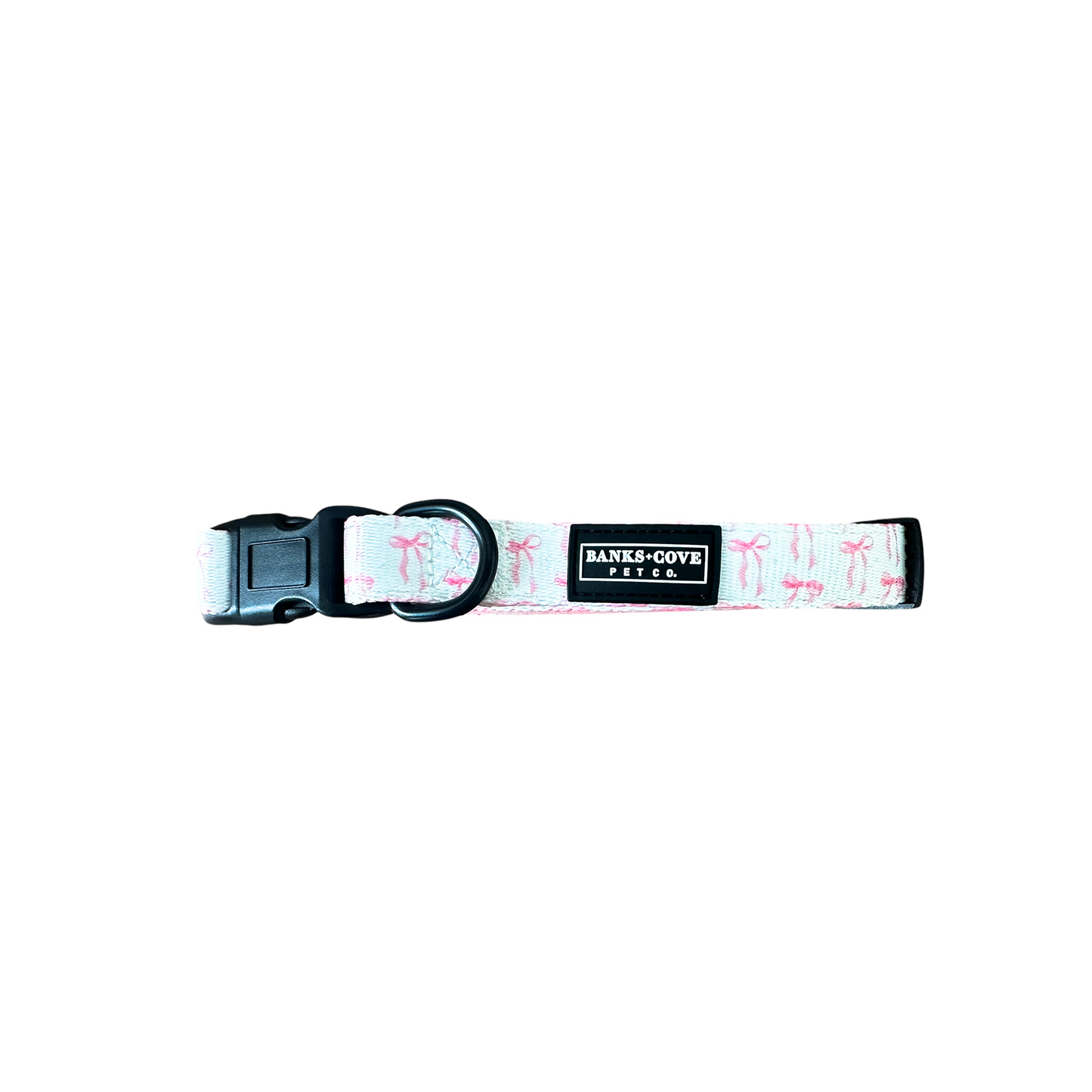 Introducing The Coquette Pooch- Dog Collar by Banks + Cove: an adjustable pink collar with black plastic buckles, a metal ring, and a charming flamingo pattern. It features a black label reading BANKS-COOTE PET CO. Perfect for your stylish canine friend.