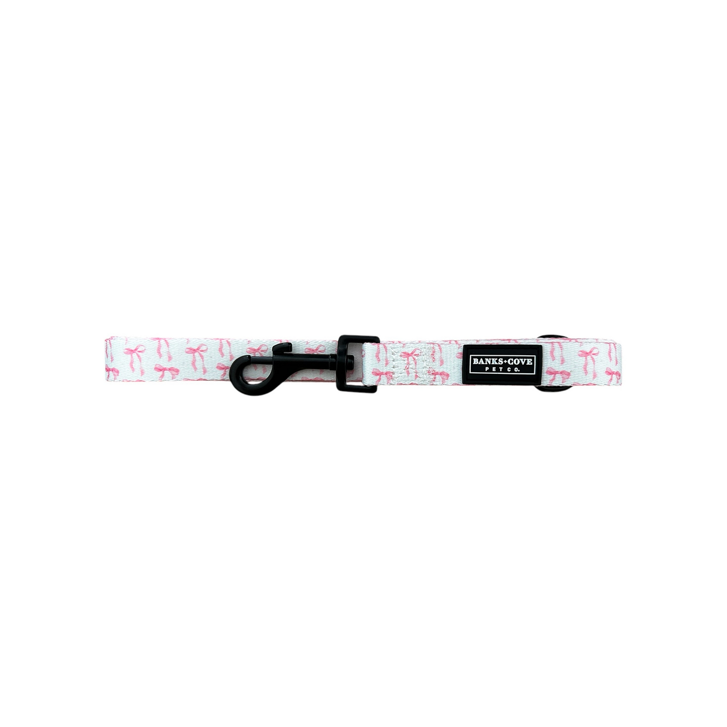 A white pet collar with a pink flamingo pattern and black buckle, featuring a BAYLY & CO. tag on a small black patch, complements the Banks + Cove Coquette Pooch Dog Leash. This stylish ensemble is displayed horizontally against a white background for your chic canine companion.