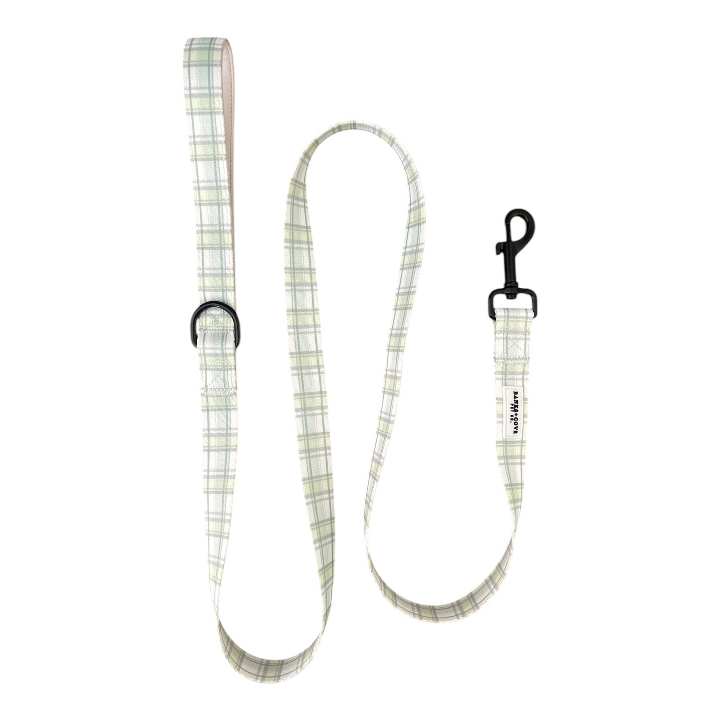 The Banks + Cove Plaid About You Dog Leash features a classic light-colored plaid pattern, a black metal clip, and an adjustable loop handle for comfort.