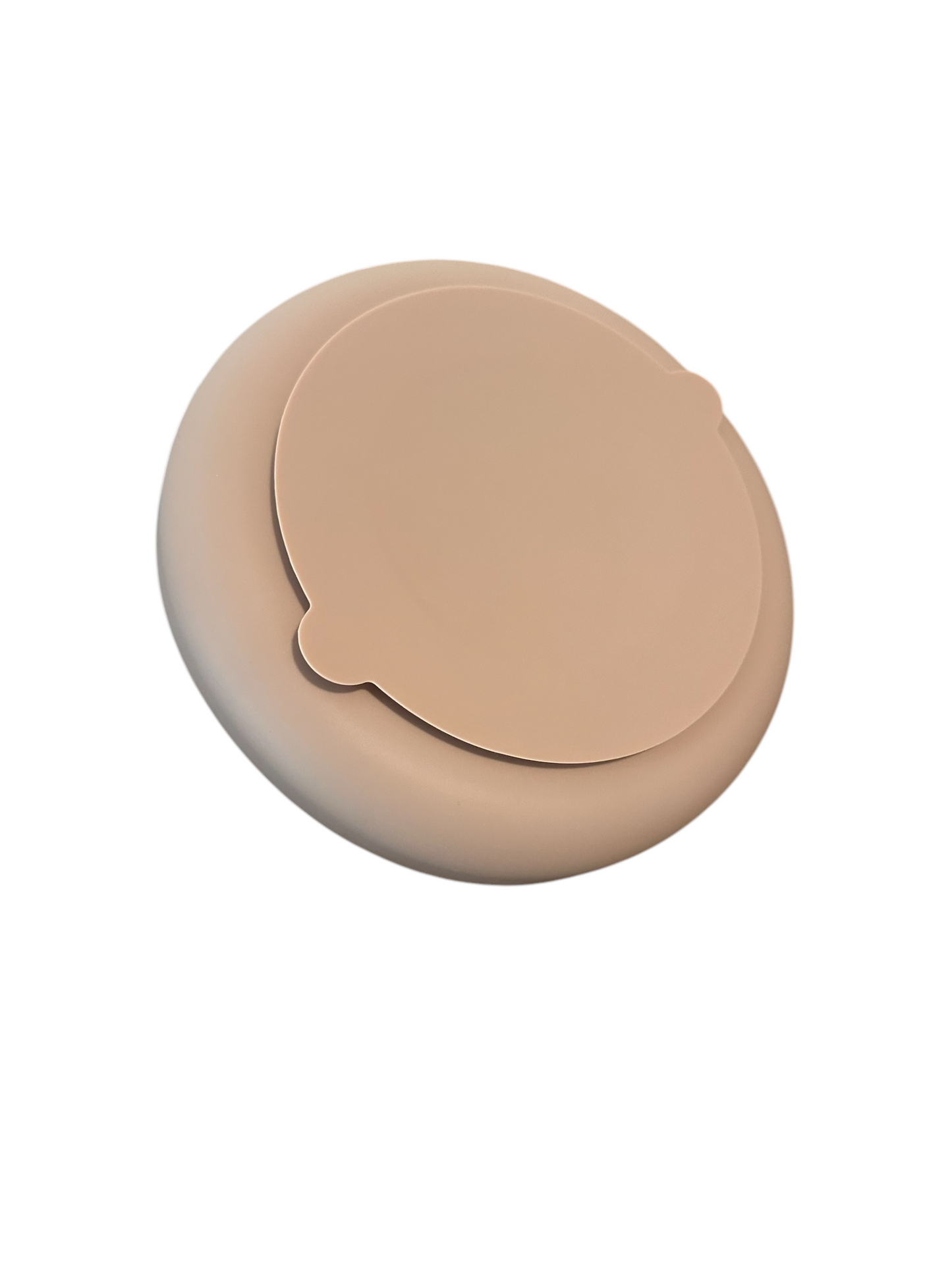 A light brown, round, and flat object with a slightly raised circular feature on top, resembling the Double Rainbow Slow Feeder from Banks + Coves luxury pet supplies line, against a white background.