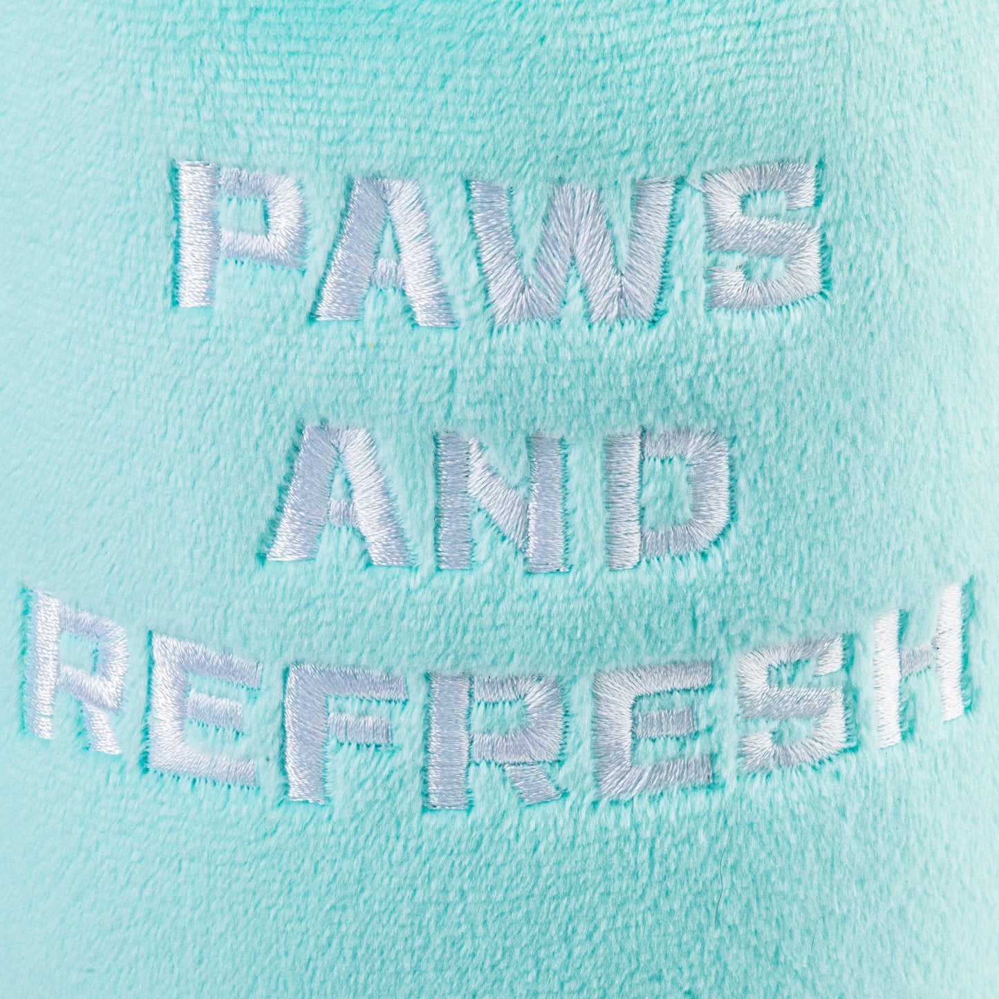 A close-up of teal fabric shows PAWS AND REFRESH embroidered in white, with a soft and plush texture ideal for cuddling with your Haute Diggity Dog Snuggly Cup.