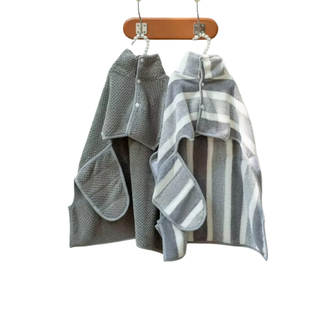 Two Banks + Cove gray childrens Bathrobe Drying Towels with hoods hang on hooks against a white tile wall. One has a waffle pattern, the other features white and gray stripes, ideal for pet pampering. A wooden bench is visible below.