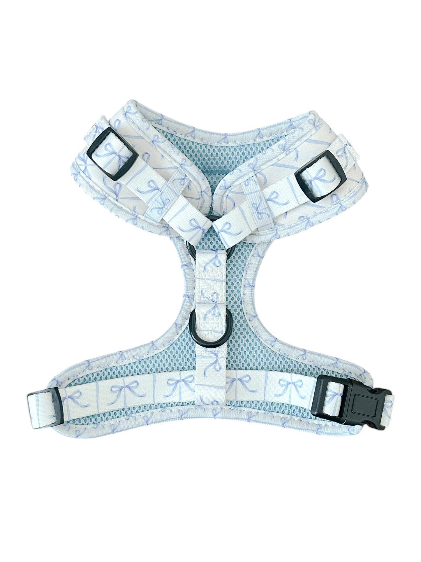 Introducing the Banks + Cove Distinguished Gentlepup Dog Harness: a white and pastel blue harness featuring a bow pattern, black buckles, metal D-ring for leash attachment, adjustable straps for a perfect fit, and breathable mesh lining for comfort on walks.
