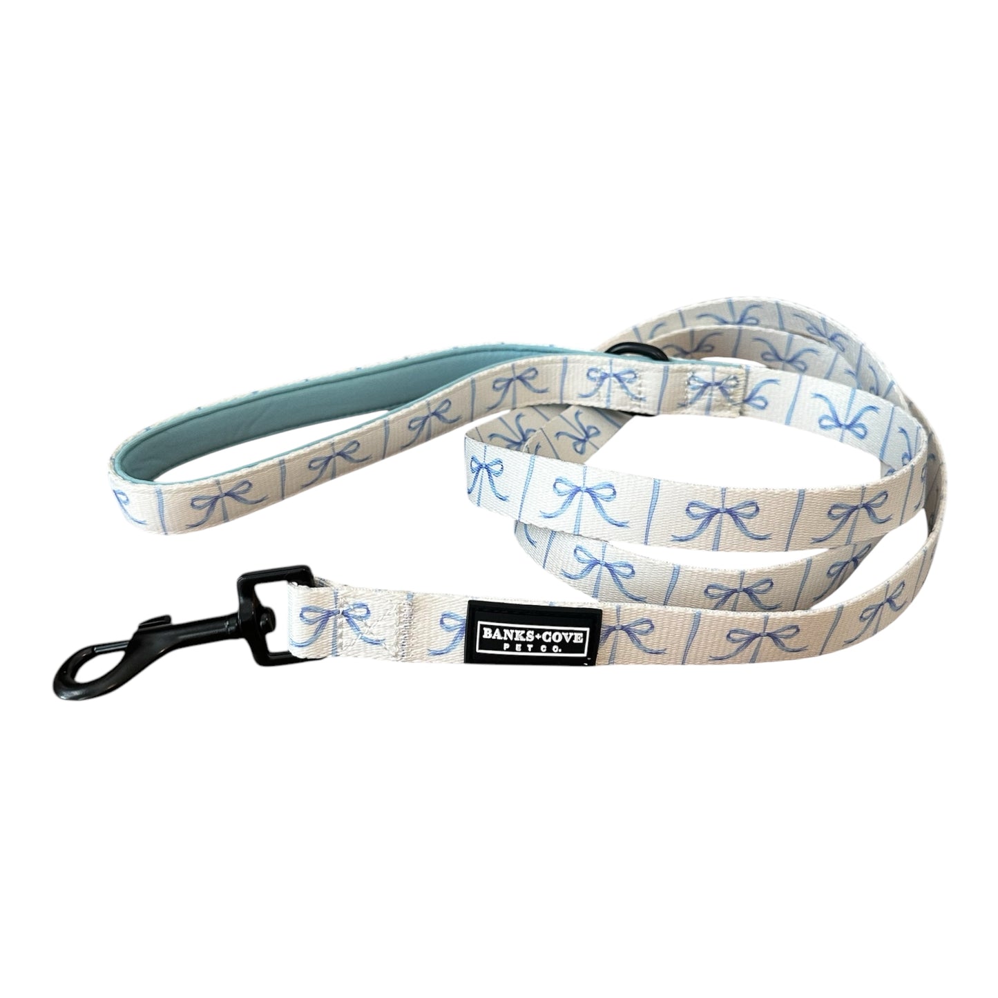 Introducing the Banks + Cove Distinguished Gentlepup Dog Leash: a stylish accessory highlighted by blue bow patterns and a black metal clasp. Its padded light blue handle offers comfort, and the black label with white BARKLEY & WAGZ text adds an elegant touch.