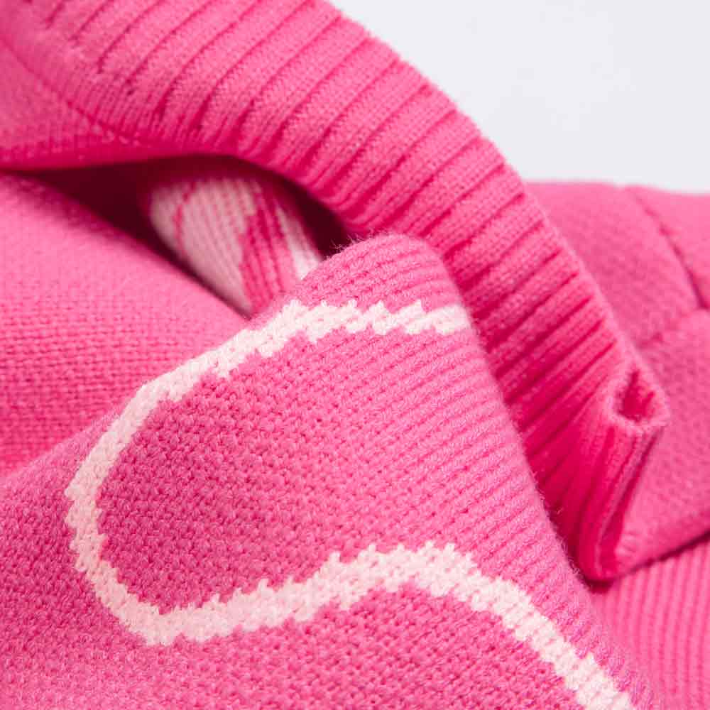 A close-up of Fitwarms Bowknot Dog Sweater showcases pink knit fabric with light pink patterns and a subtle bowknot design. The texture features ribbing and smooth sections, resembling a cute sweaters cozy circular neckline for visual contrast.