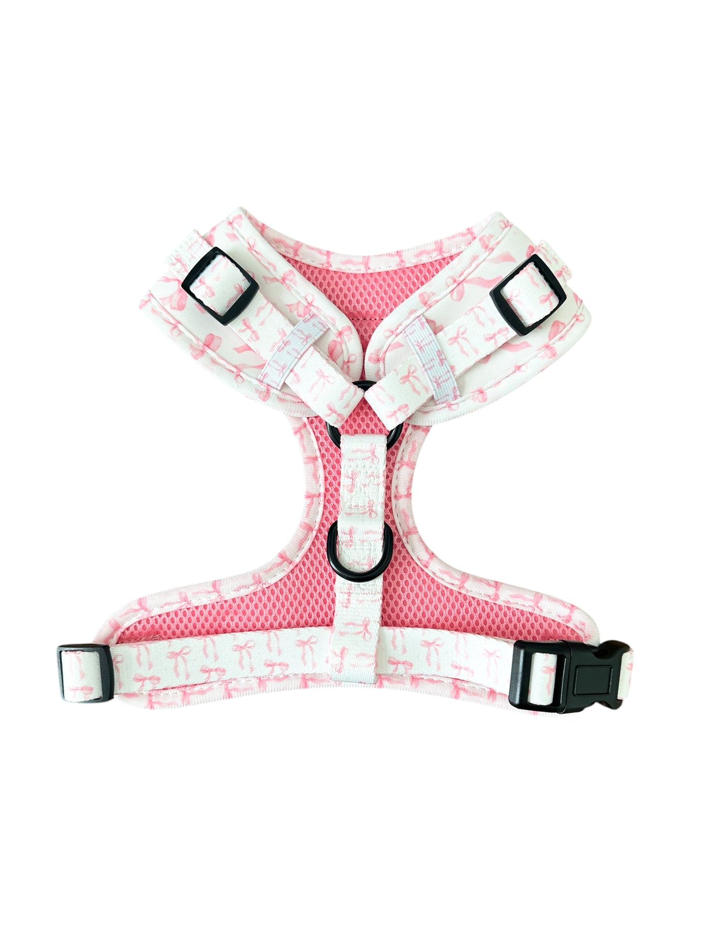 Banks + Cove presents The Coquette Pooch Dog Harness: a stylish pink and white floral-patterned harness with adjustable straps, padded comfort, black buckles for a secure fit, and a D-ring for easy leash attachment. Keep your dog comfortable and chic on every walk.