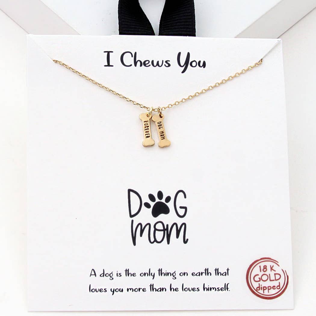 The I Chews You – Dog Mom Bone Charm Necklace by Banks + Cove features two bone-shaped pendants labeled Dog Mom with an 18K gold-dipped tag. The packaging says I Chews You and showcases a paw print, celebrating a dogs love while adding elegance to the piece.